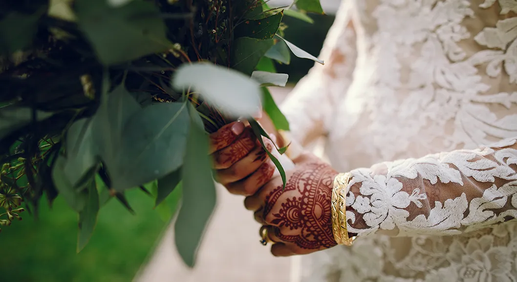 Bride's hands with henna holding a bouquet